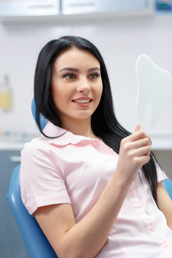Beautiful girl smiles and looks in the mirror dental clinic