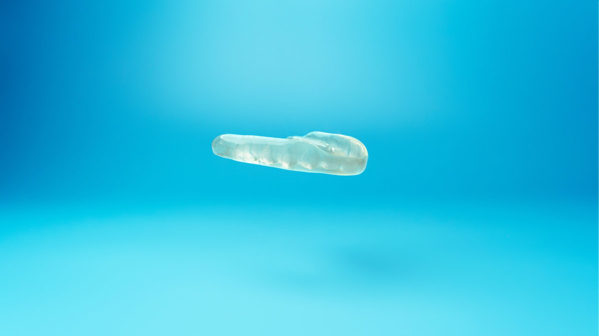 Individual myorelaxing mouthguard on a blue background. Muscle relaxant mouth guard or night mouth guard treatment of teeth grinding, bruxism and TMJ dysfunction.