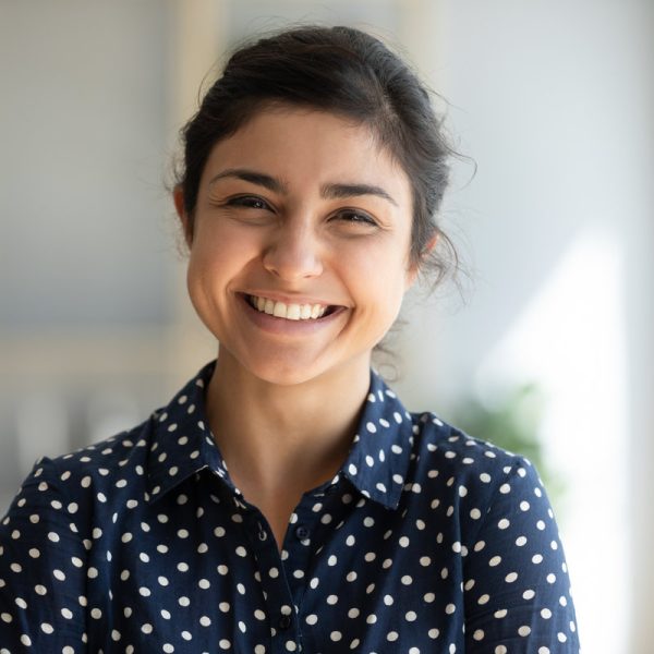 Cheerful indian girl standing at home office looking at camera Cheerful beautiful indian girl student professional standing at home in office looking at camera, happy confident entrepreneur hindu lady laughing face posing alone, head shot close up view portrait